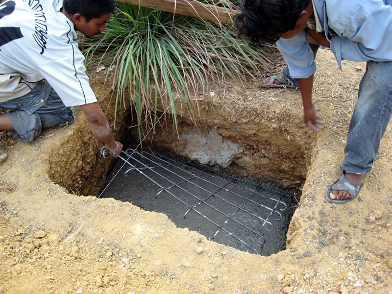 Workers setting rebar in an excavated footing for a new foundation pier